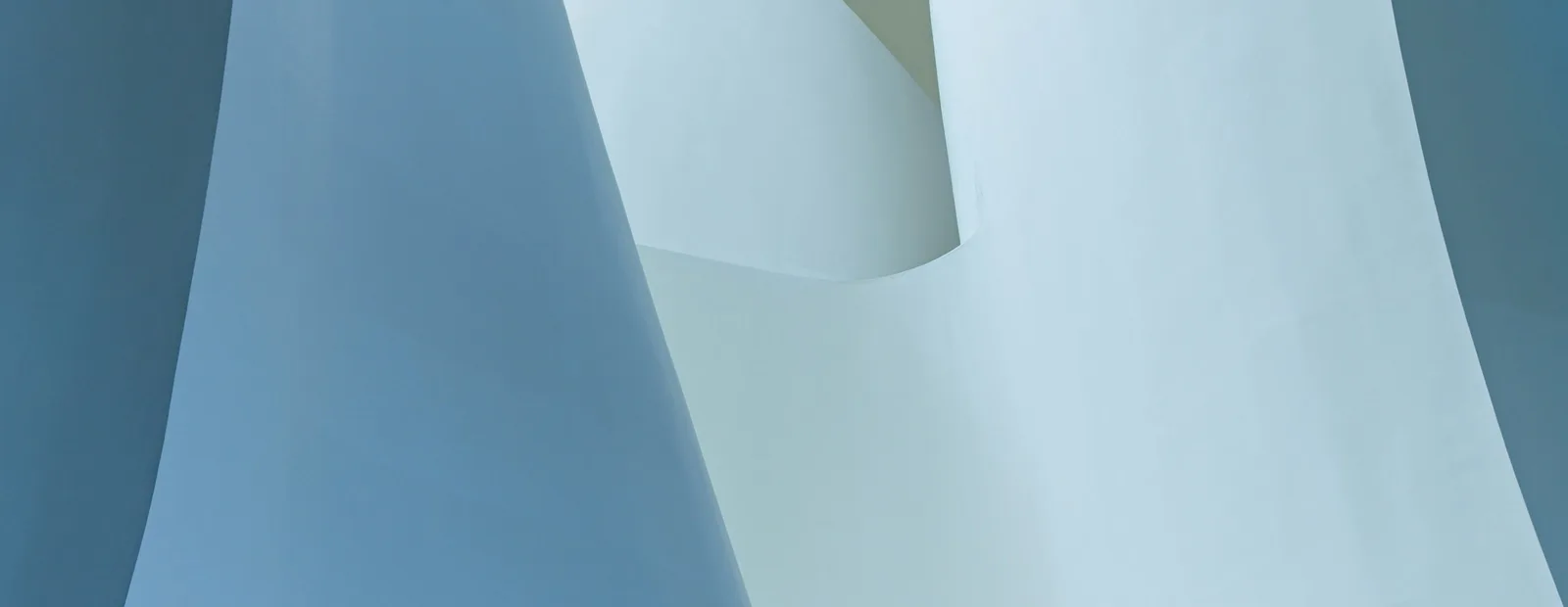 Courbes architecturales blanches et bleu pâle qui se chevauchent, vue rapprochée d’une structure aux lignes sculpturales