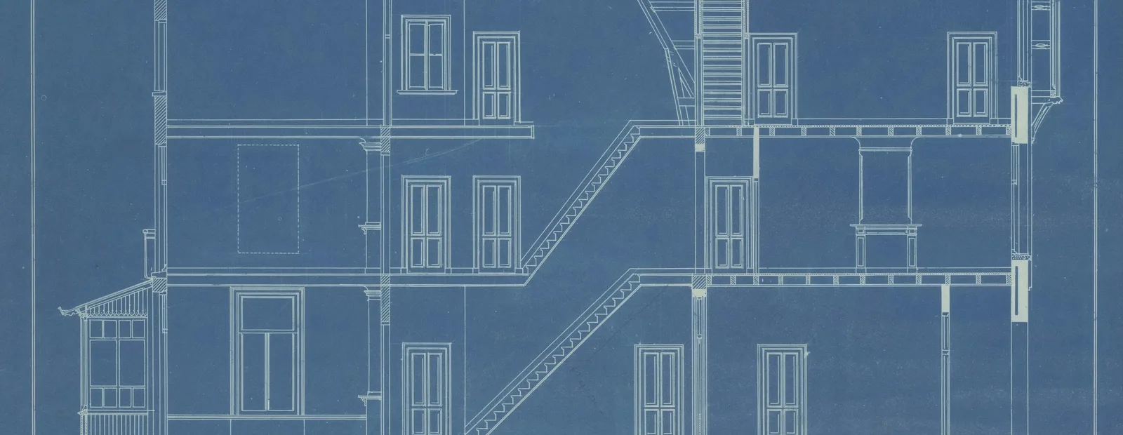 Plan d’architecte en bleu montrant la coupe d’un immeuble de plusieurs étages, avec escaliers et fenêtres
